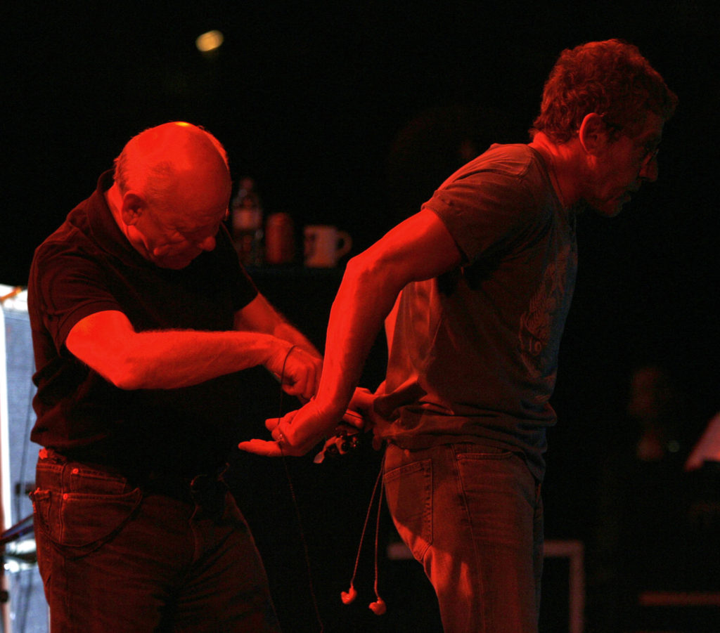 The Who's onstage sound engineer Bob Pridden adjusts Roger Daltrey's inner ear monitors during The Who's performance at Indian Wells Tennis Stadium, Palm Springs, CA, on November 11, 2006.