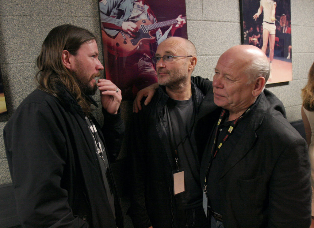 Onstage Sound Engineer Bob Pridden chats with Genesis drummer Phil Collins (middle) and another friend in the hallway backstage at Madison Square Garden following The Who's show.